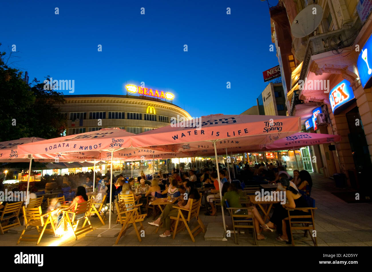 People in busy sidewalk cafe bar at night Plovdiv Bulgaria Stock Photo