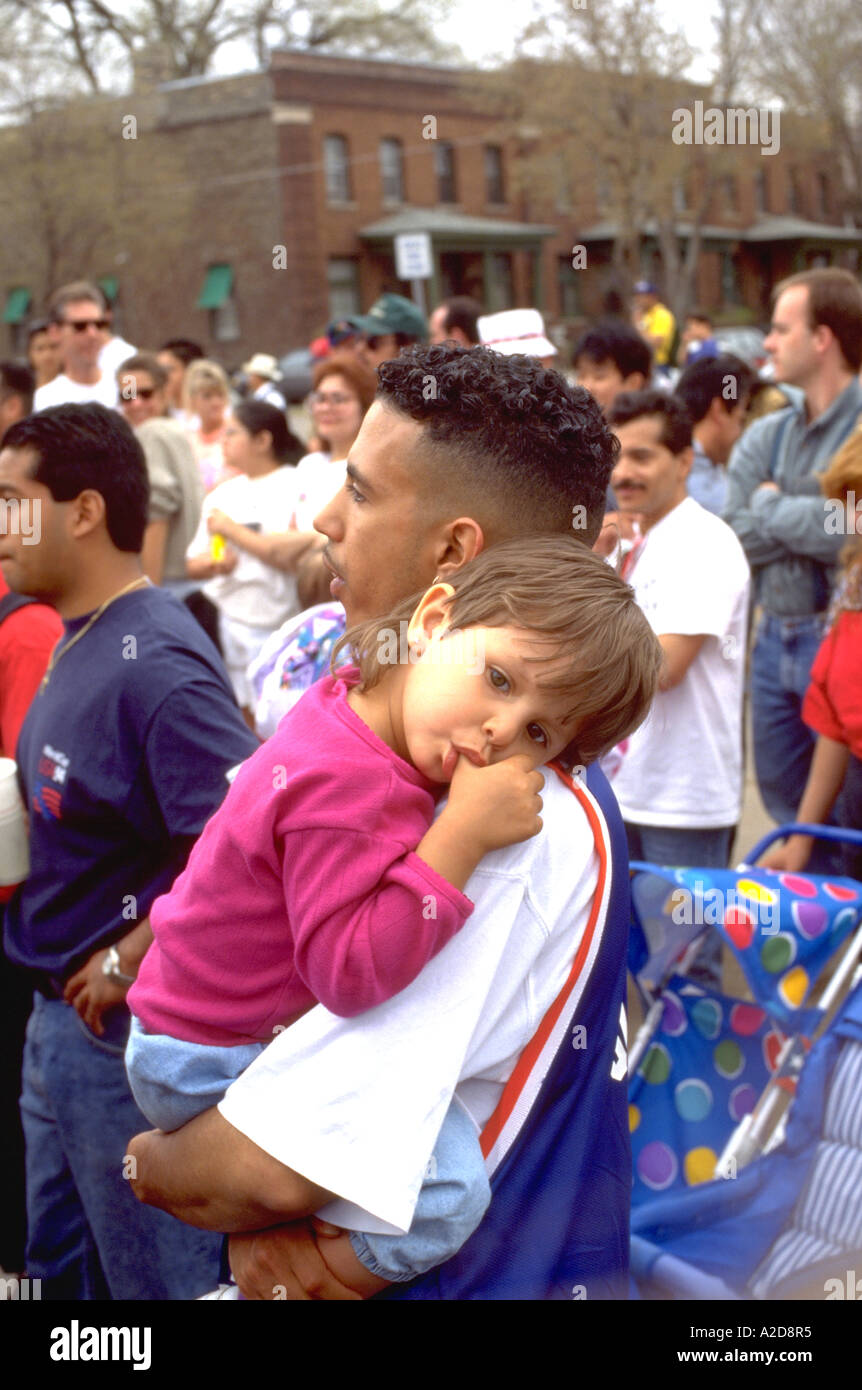 Father carrying thumb sucking daughter  at Cinco de Mayo age 24 and 3. St Paul Minnesota USA Stock Photo