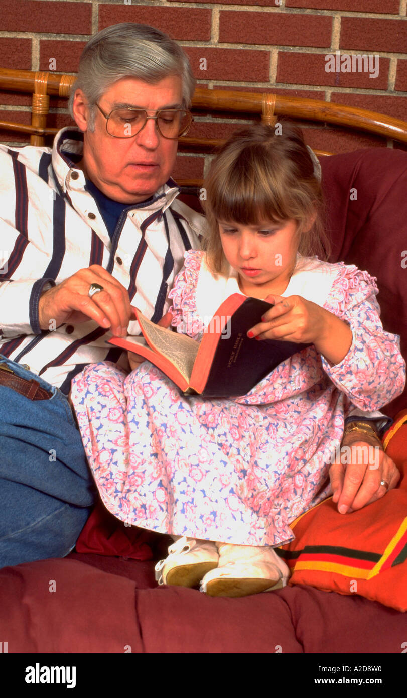 Grandpa age 60 studying bible with granddaughter age 5 Western Springs Illinois USA Stock Photo
