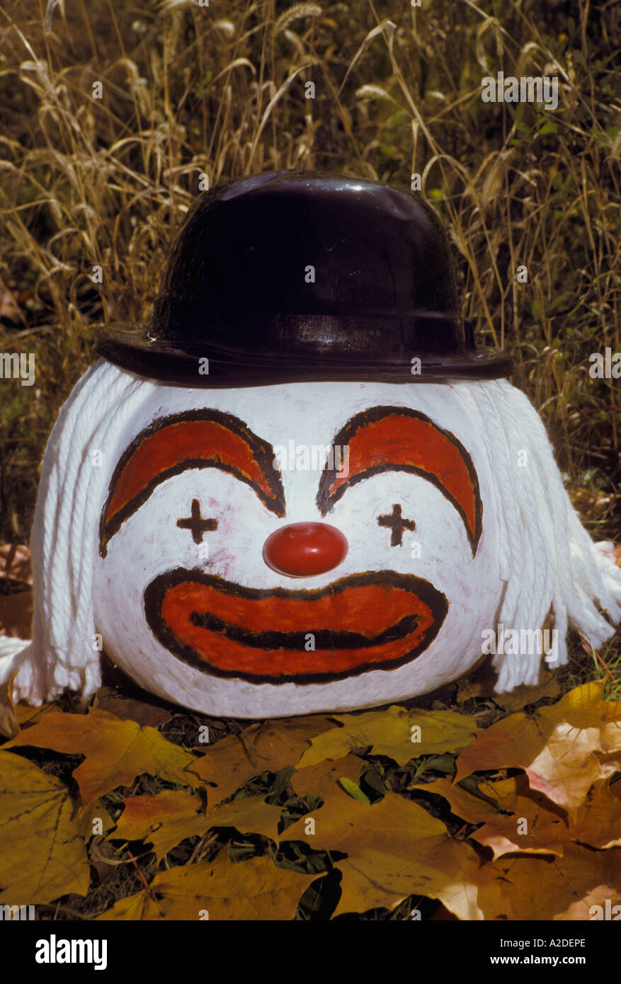 Clown painted pumpkin sitting on the ground. Stock Photo