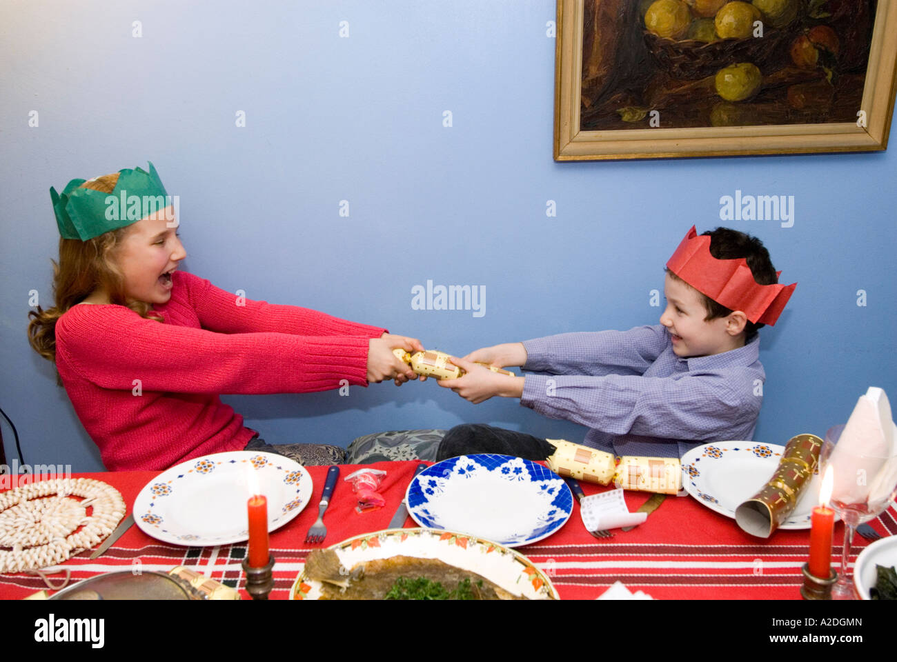 Brother and sister pulling Christmas cracker at the lunch table England UK Stock Photo