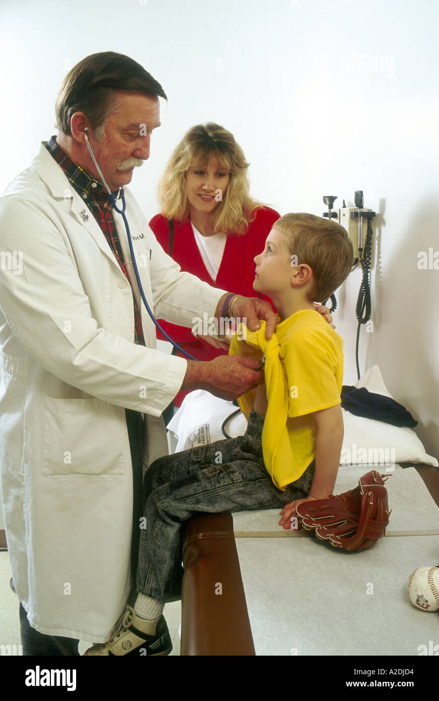 Doctor examins boy mother looking on Stock Photo