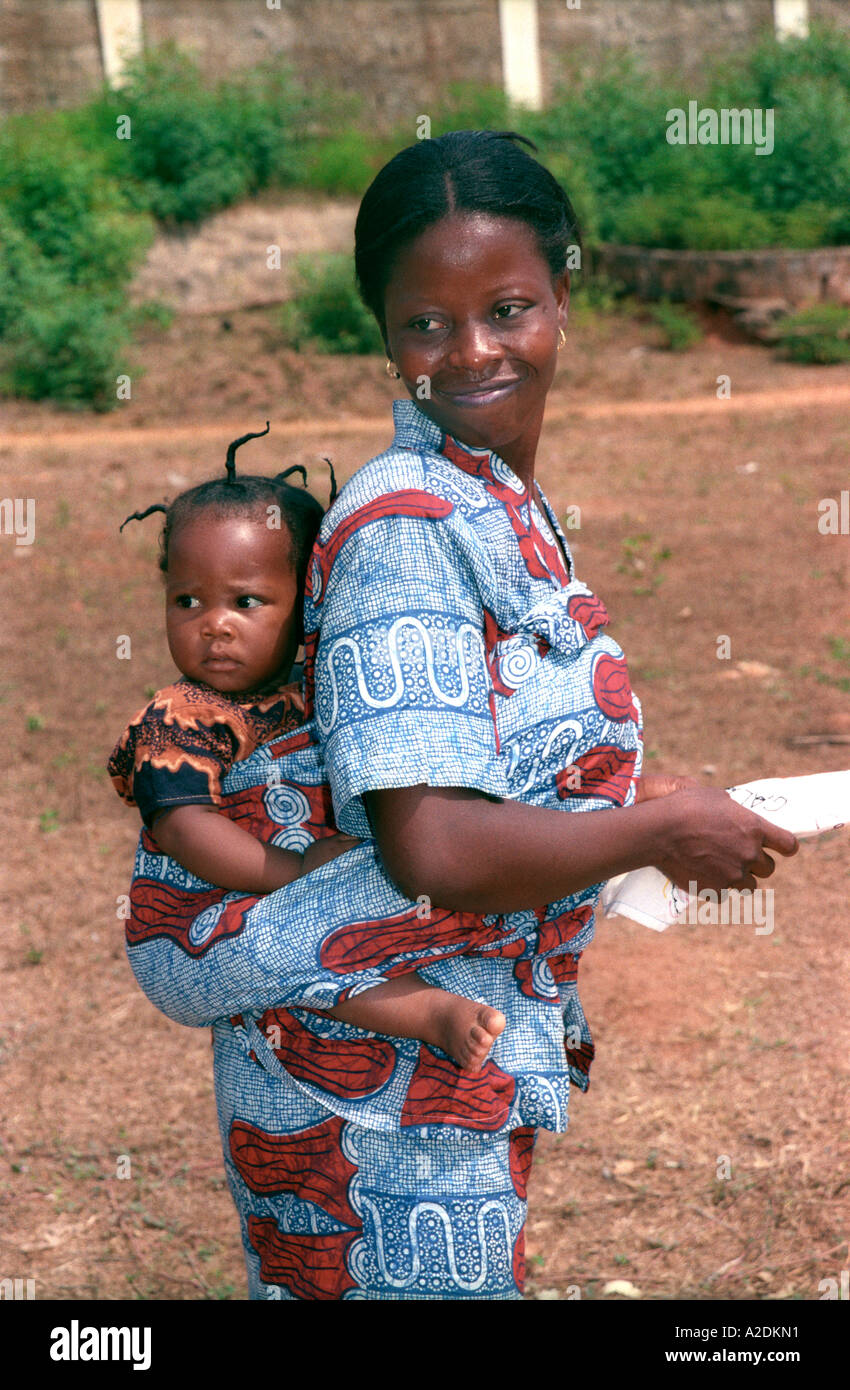 African woman with child on back wearing locally designed and printed dress Stock Photo