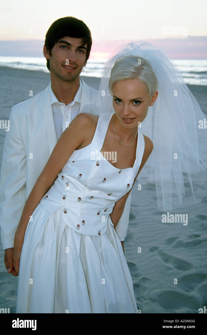 1207834 outdoor summer day beach sea water couple woman man young 25 30  blonde dark haired wedding dress veil suit white marr Stock Photo - Alamy
