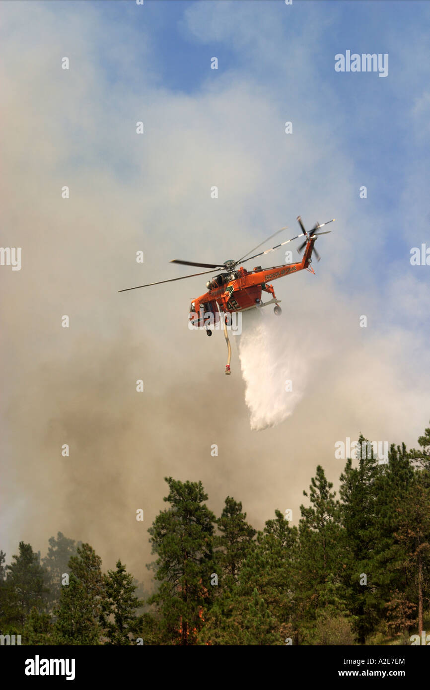 Sikorsky helicopter dropping water on a forest fire with smoke in the
