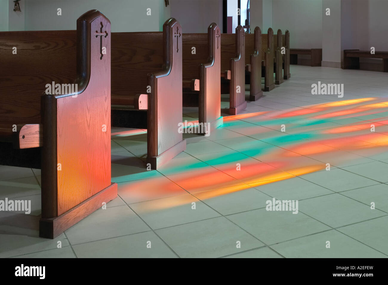 Church Pews With Light From Stained Glass Window  Shining On The Floor Making A Colorful Pattern In Roman Catholic Church, USA Stock Photo