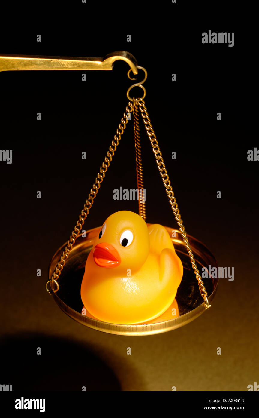 Yellow rubber duck on a brass scale Stock Photo