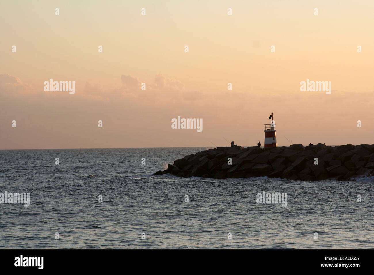 Fishermen Silhouette at the lighthouse Alvor in the evening sun Algarve Portugal Stock Photo