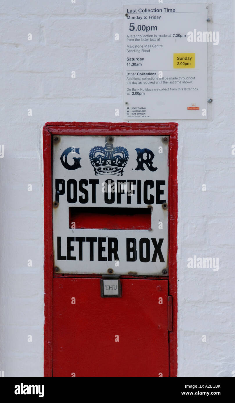 Red letter box set in a white painted brick wall with a black and white enamel sign saying GR