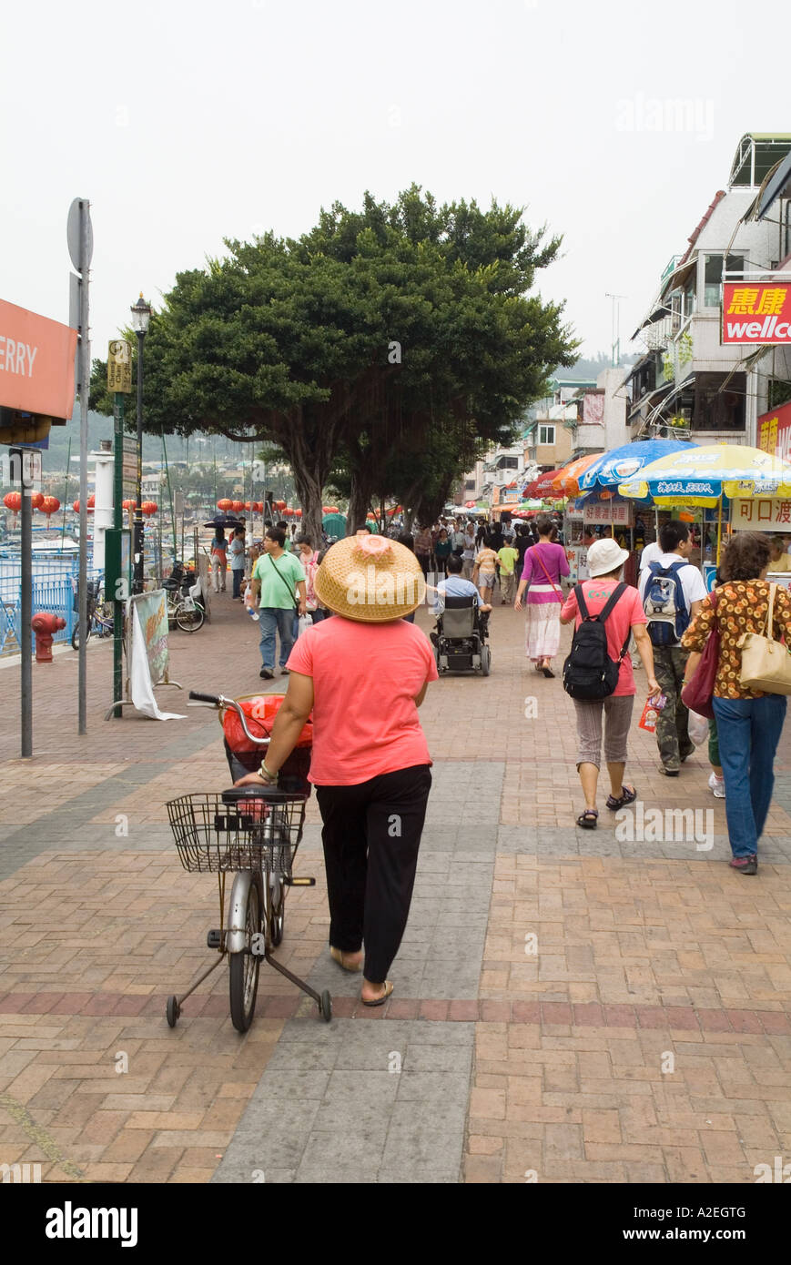 dh Woman Cooly hat CHEUNG CHAU HONG KONG Chinese crowds Harbour waterfront promenade straw hatted lady with bicycle Stock Photo