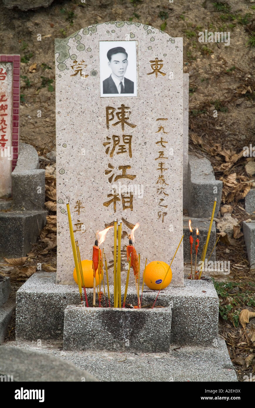 dh Chinese gravestone CHEUNG CHAU HONG KONG Joss sticks and orange offering graveyard grave stone in cemetery tombstone stones tomb Stock Photo