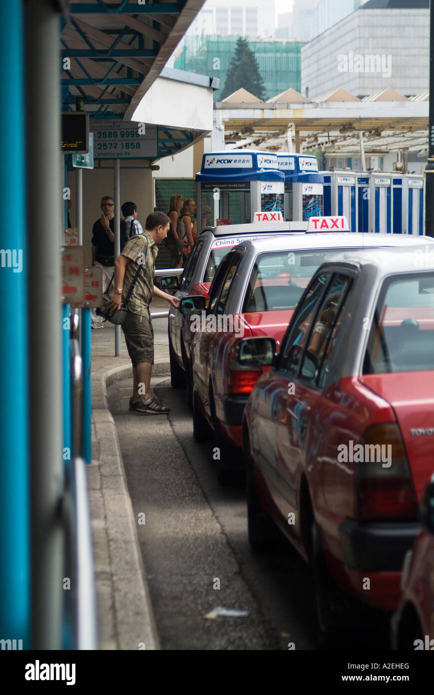 dh  CENTRAL HONG KONG Man opening door of taxi Star Ferry taxi rank queue taxicab cab line wait Stock Photo