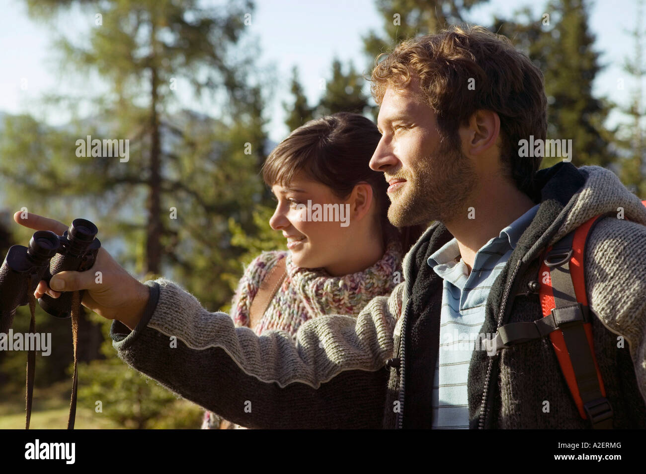 Young couple walking on mountains, man holding binocular Stock Photo
