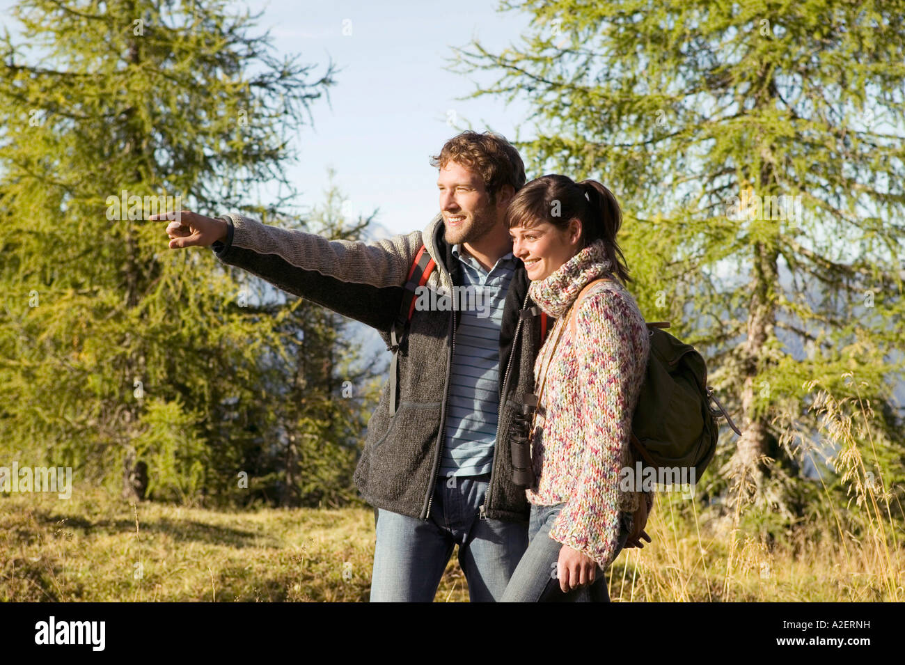 Young couple walking in meadow, man pointing Stock Photo
