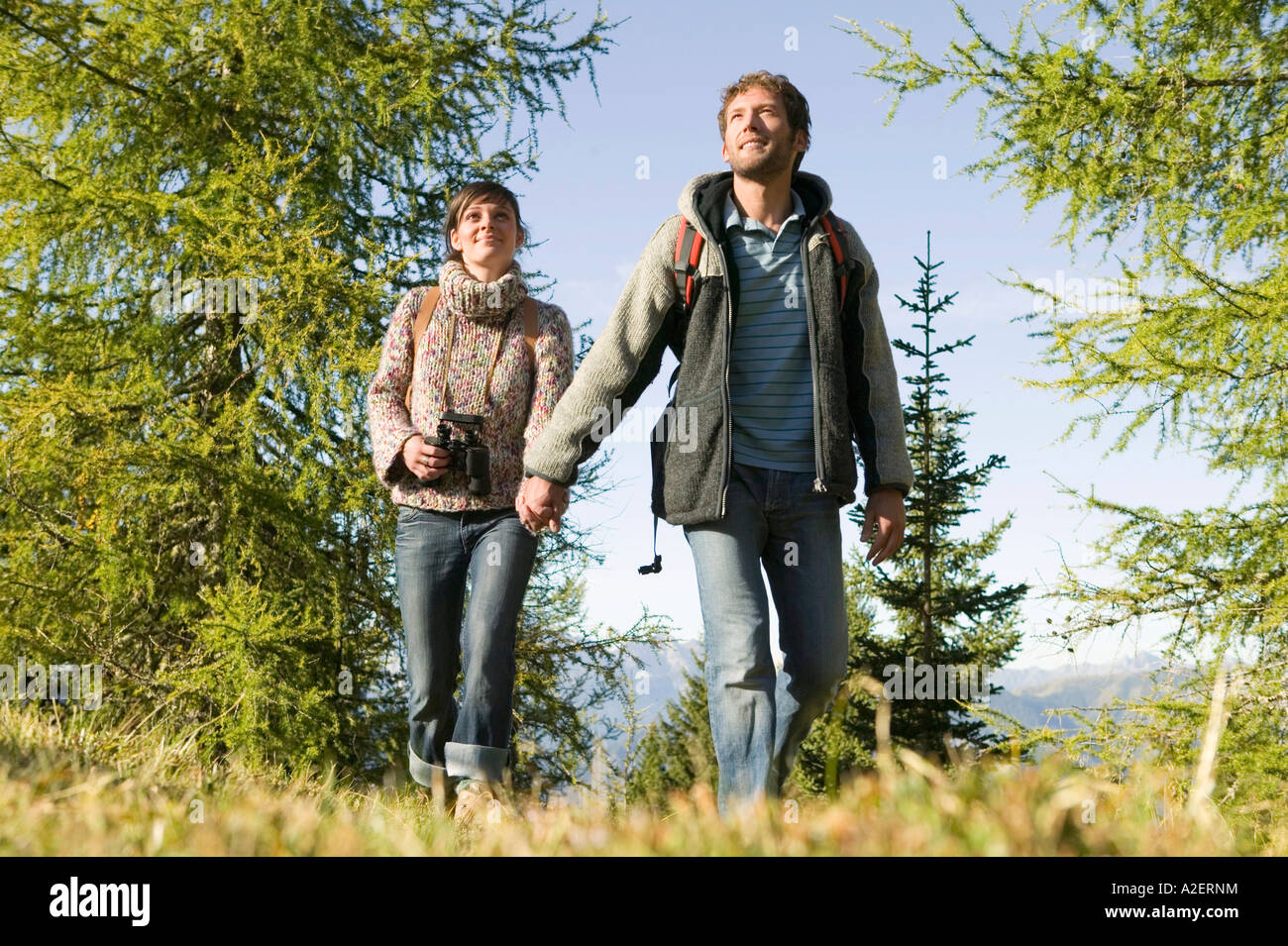 Young couple walking in meadow holding hands Stock Photo