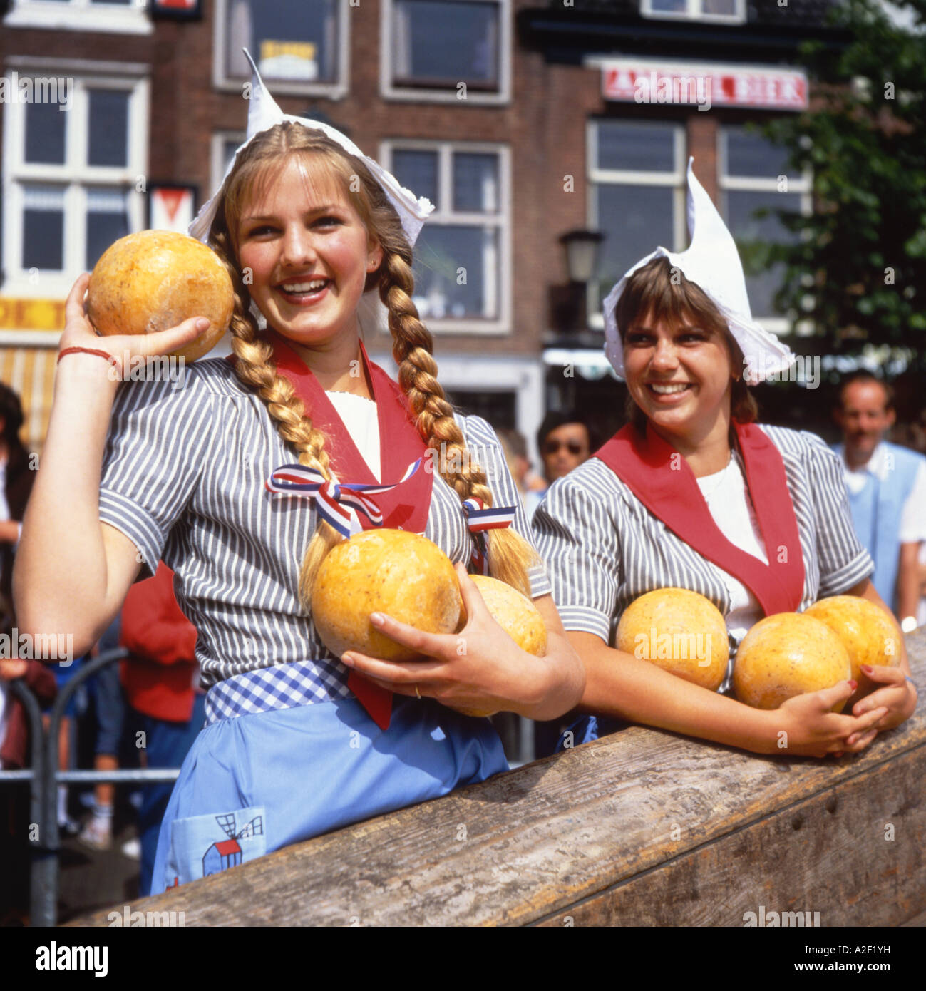 Two Dutch girls in traditional dress selling cheeses at Alkmaar Market ...