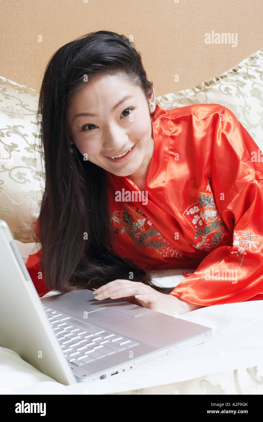 Portrait of a young woman lying on the bed with a laptop Stock Photo ...
