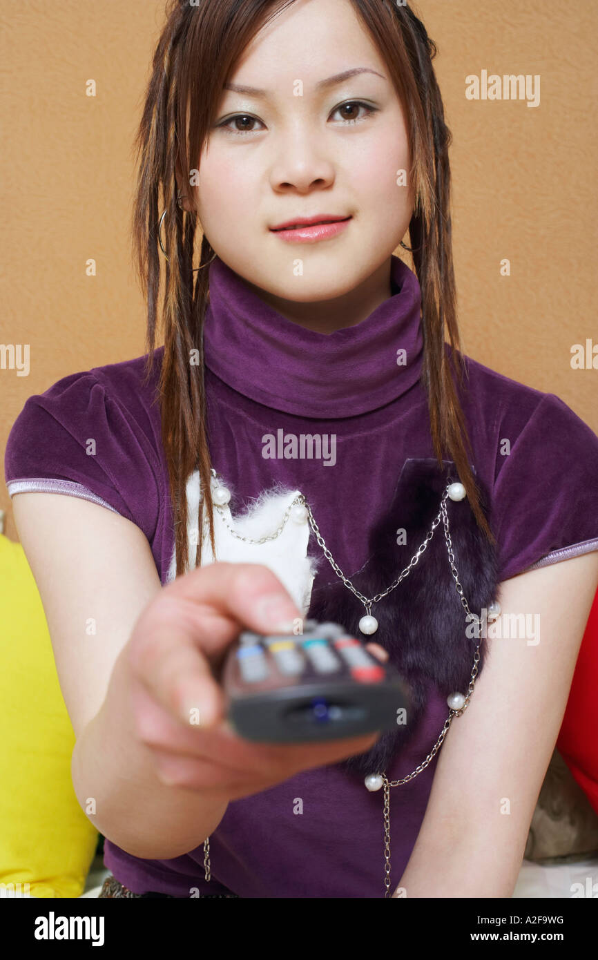 Portrait of a young woman holding a remote control Stock Photo - Alamy