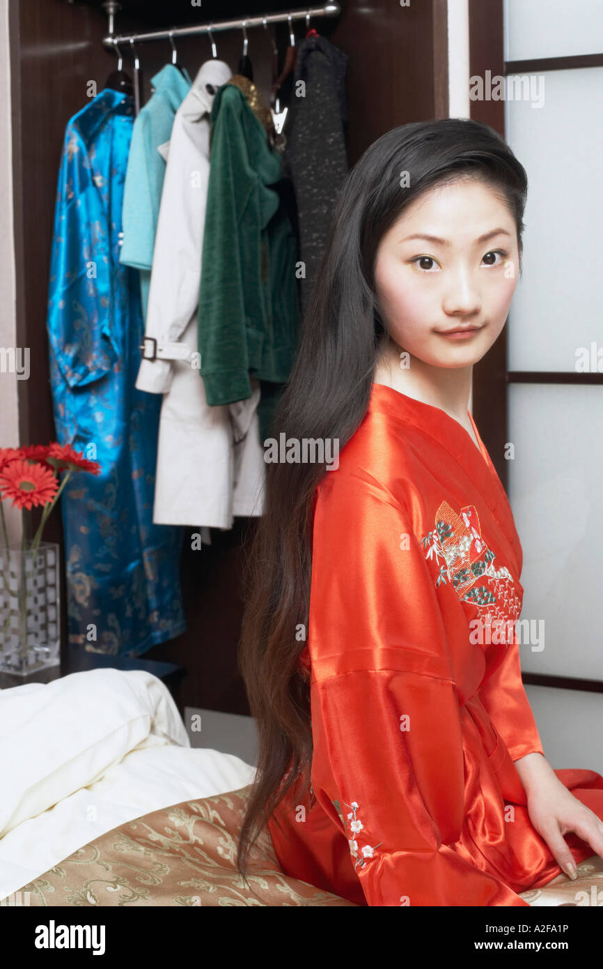 Portrait of a young woman sitting on the bed Stock Photo - Alamy