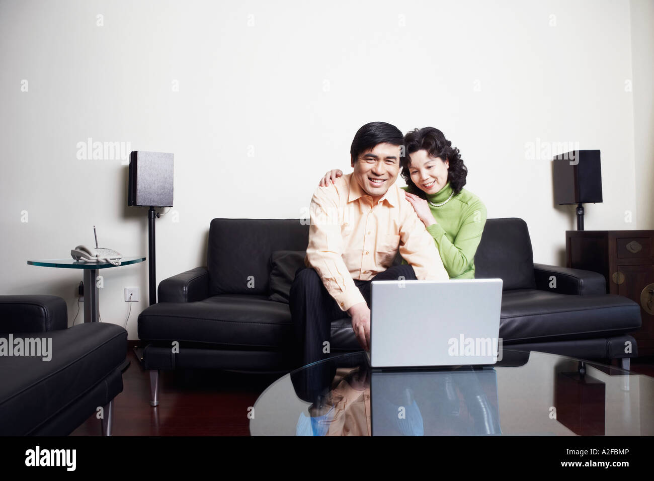 Portrait of a mature man sitting on a couch with a mature woman using a laptop Stock Photo