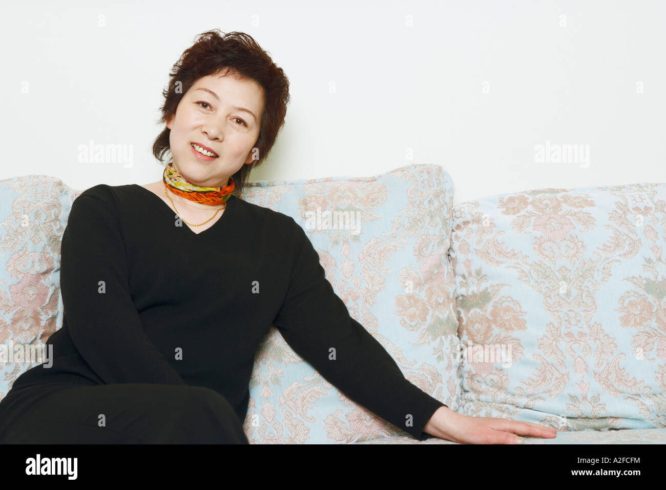 Portrait of a mature woman sitting on a couch Stock Photo - Alamy