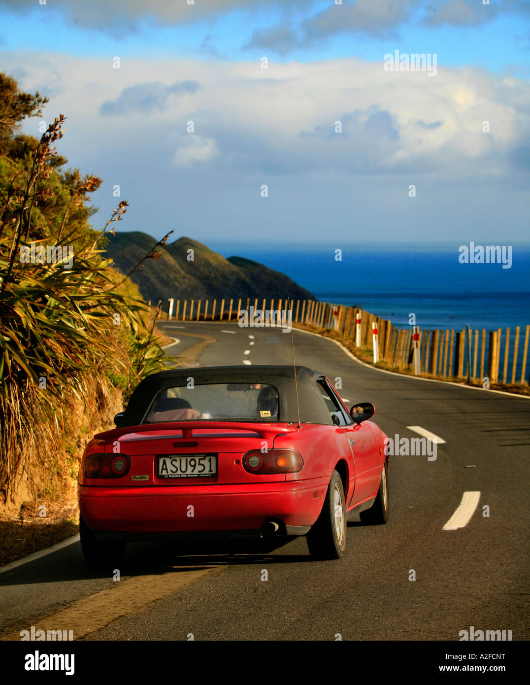 A red Mazda Sportscar on winding road scenery near Paekakariki Wellington New Zealand Stock Photo