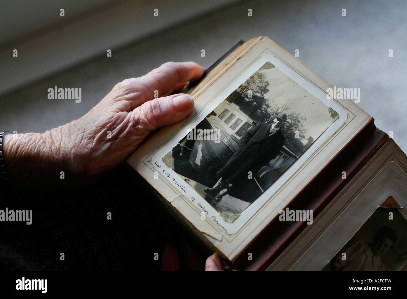 The hands of an elderly person hold a photograph album from yesteryear Stock Photo