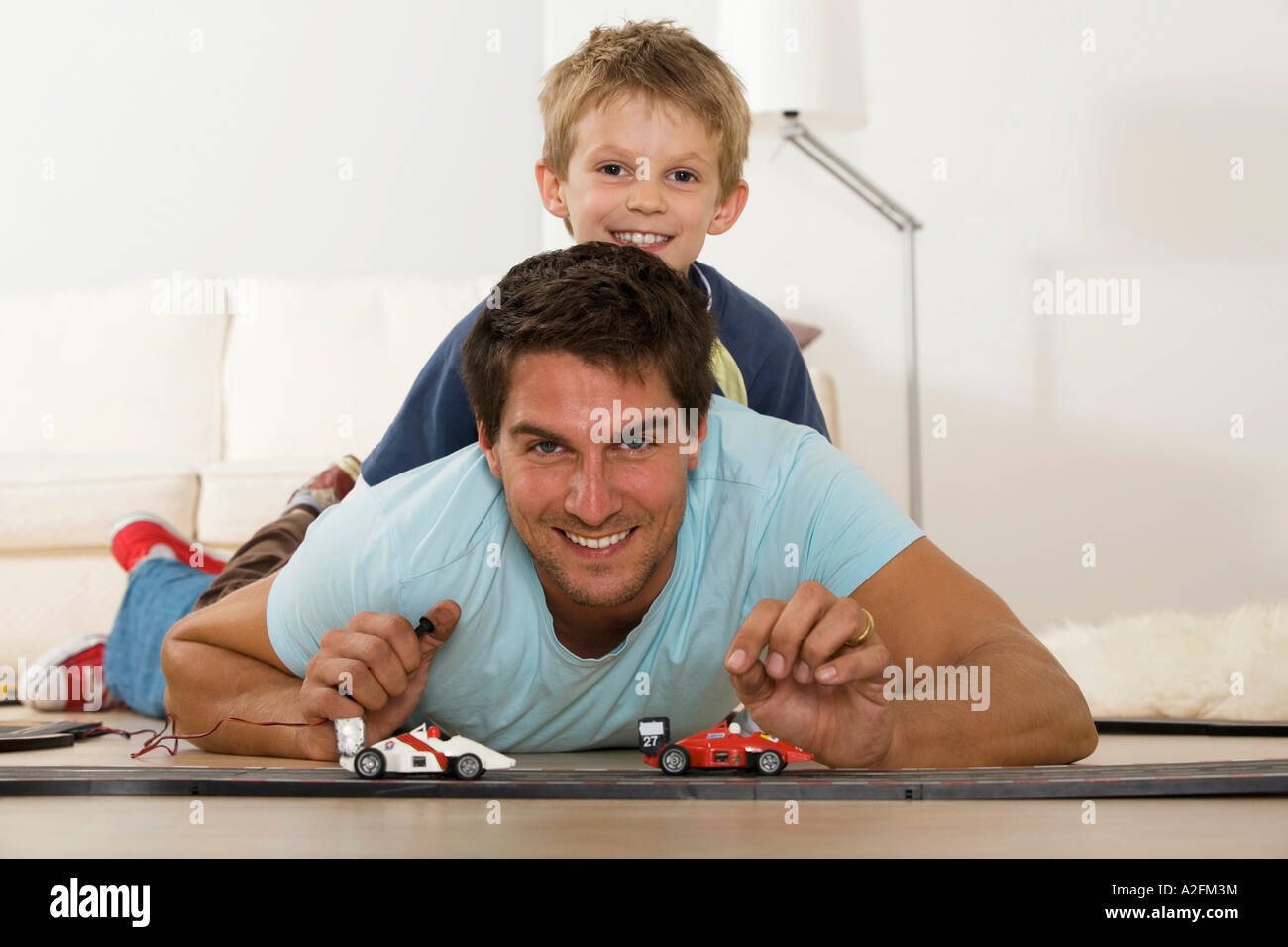 Father and son (6-7) playing with toy cars, smiling, portrait Stock Photo