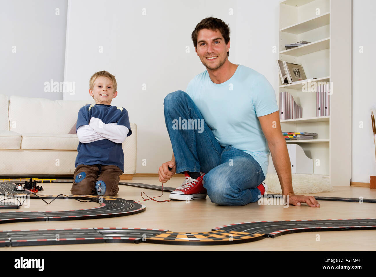 Father and son (6-7) playing with toy racetrack Stock Photo