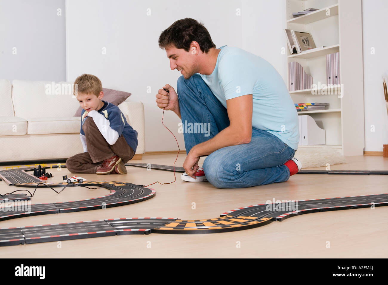 Father and son (6-7) playing with toy racetrack Stock Photo