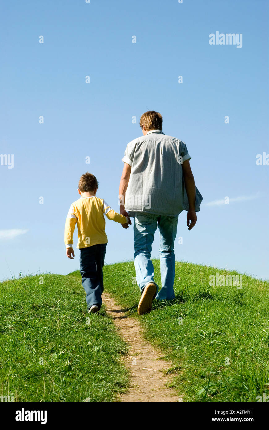 Father walking hand in hand with son, rear view Stock Photo
