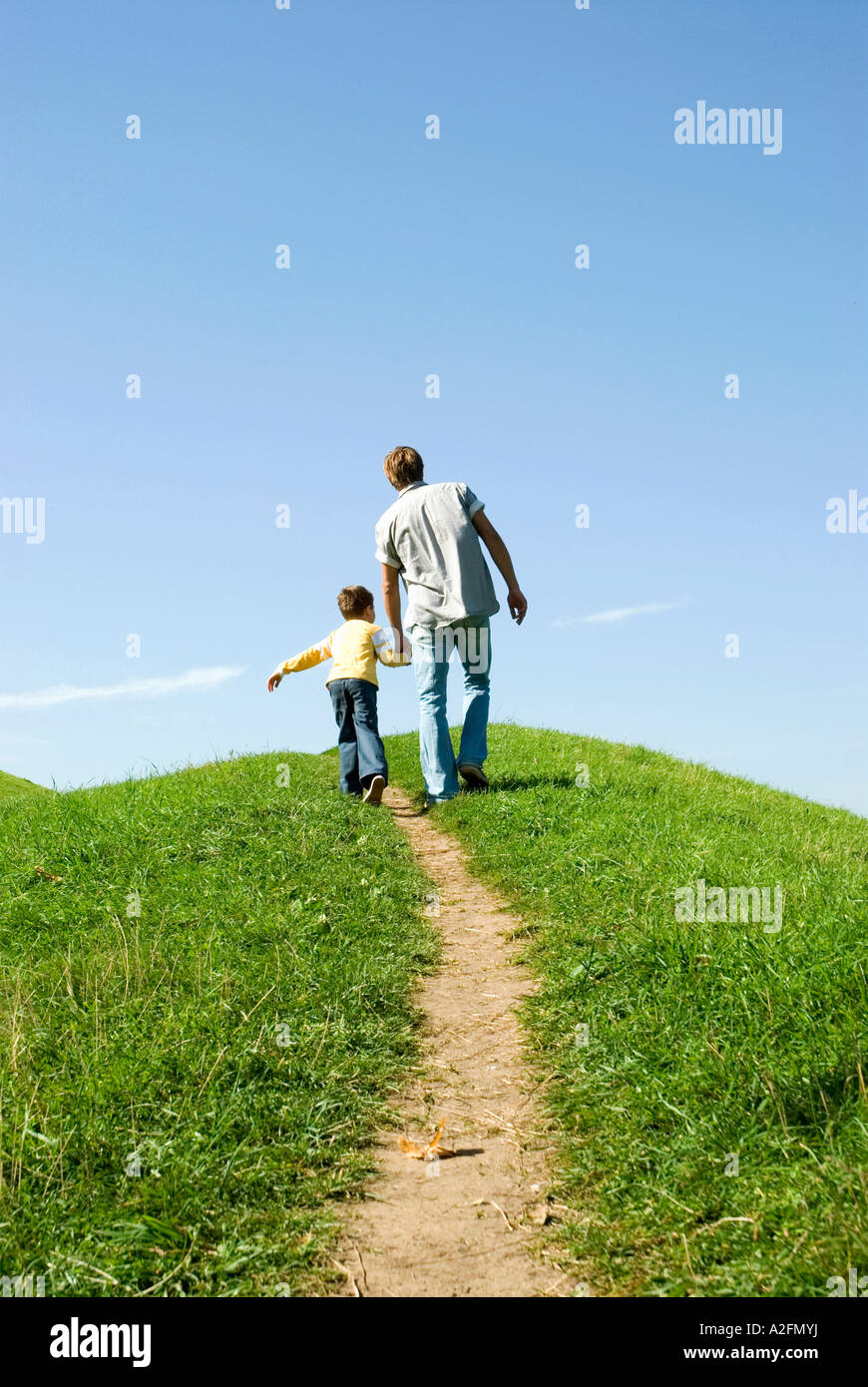 Father walking with son hand in hand, rear view Stock Photo