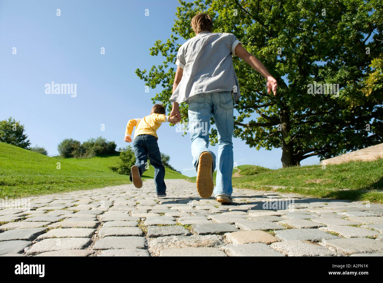 Father and son (4-7) running, hand in hand, rear view Stock Photo - Alamy