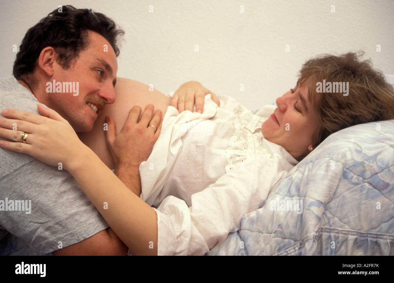 proud husband lying on wife's heavily pregnant tummy Stock Photo
