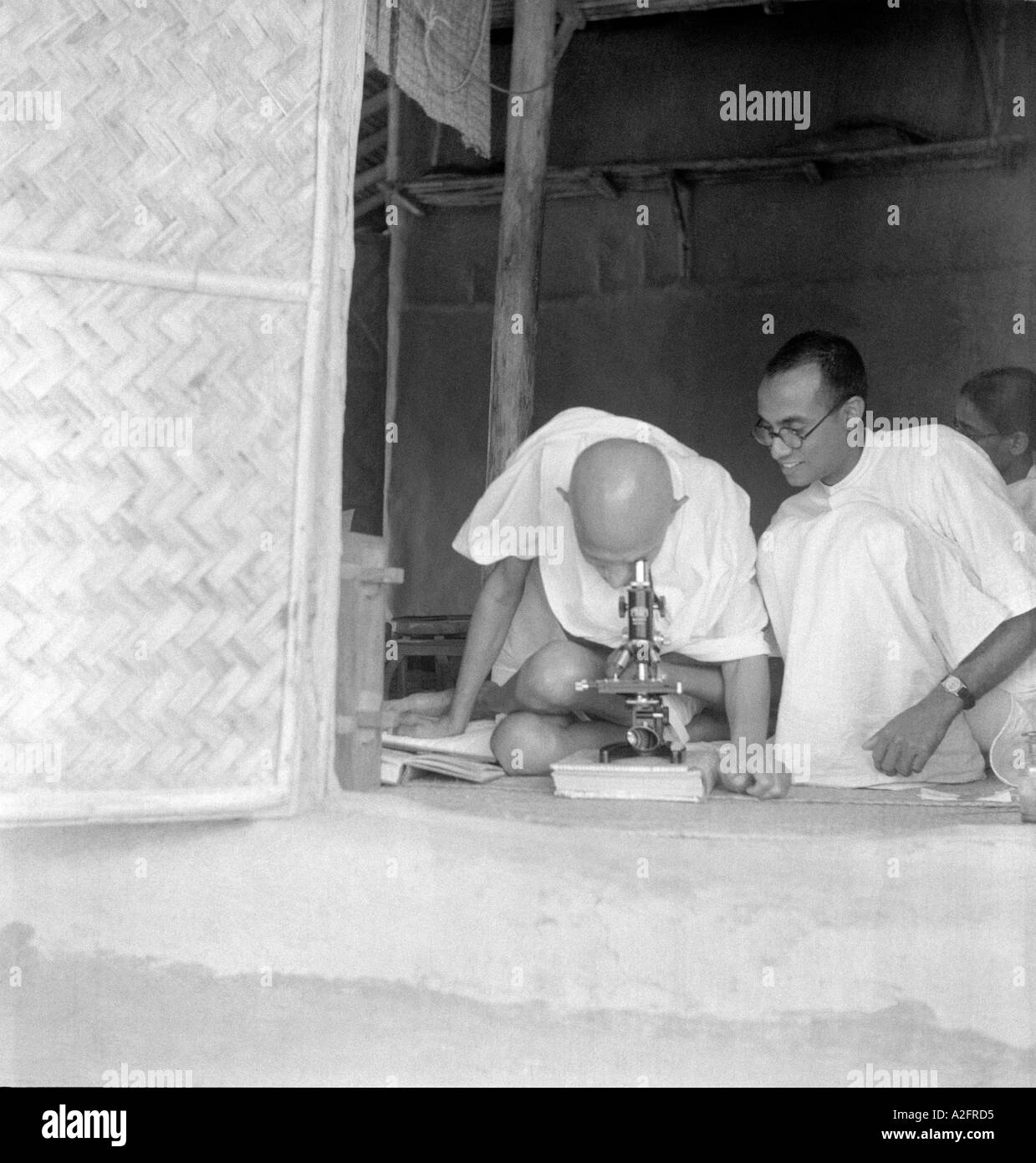Mahatma Gandhi seeing leprosy germs through microscope at Sevagram Ashram Vardha Maharashtra India 1940 Stock Photo