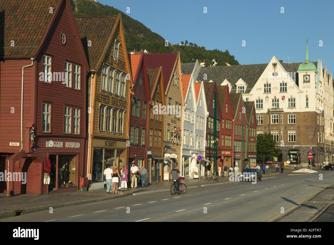 Shoppers stroll Bryggen, UNESCO World Heritage Site, ancient wood buildings along water front Stock Photo