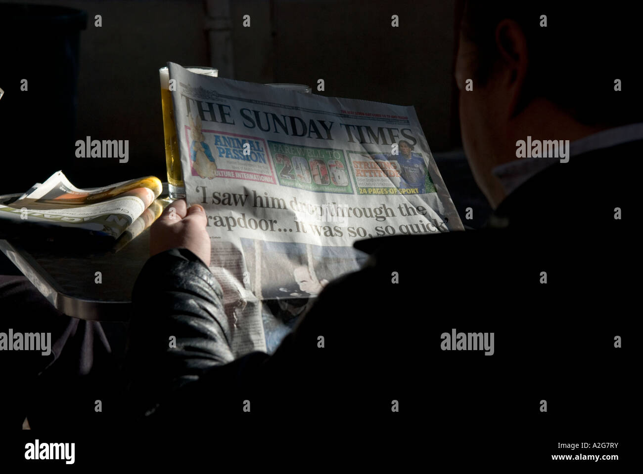 looking over the shoulder of a man reading the sunday paper with headlines about execution of saddam hussein Stock Photo