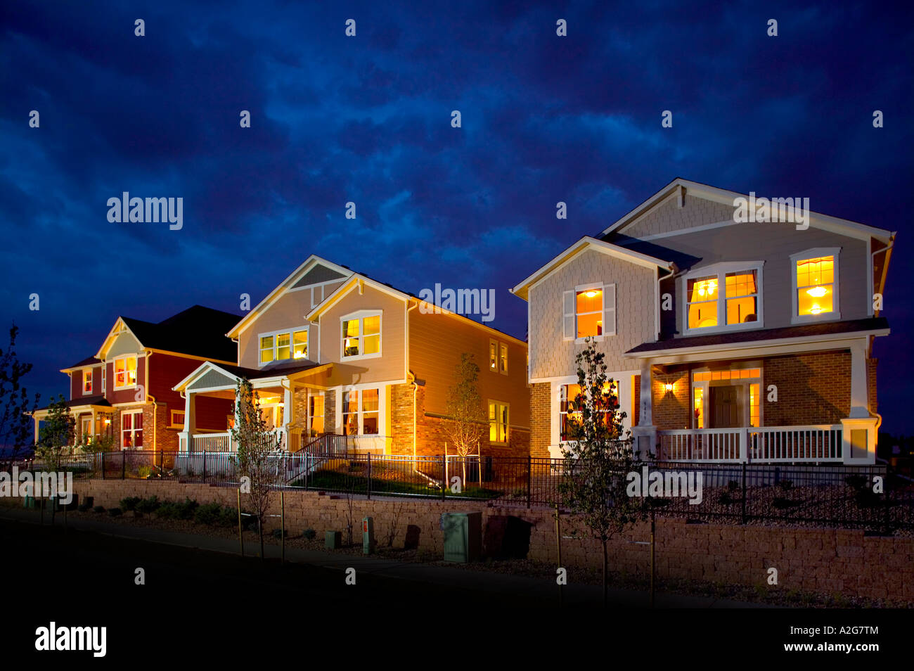 Exterior street view of three middle class homes with lights on taken