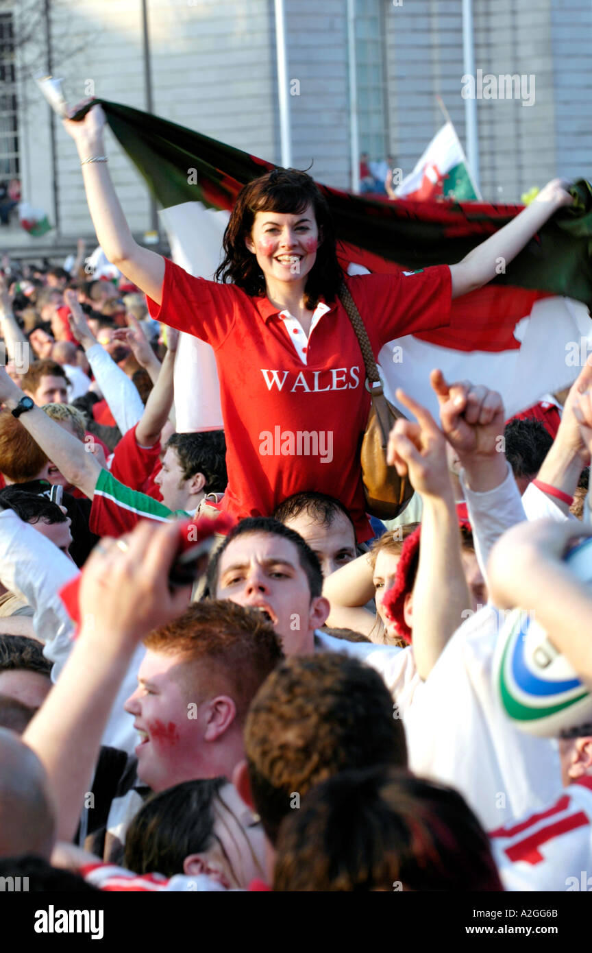 Young woman Welsh rugby fan wrapped in red dragon flag celebrating Wales winning a 6 six nations match in Cardiff South Wales Stock Photo