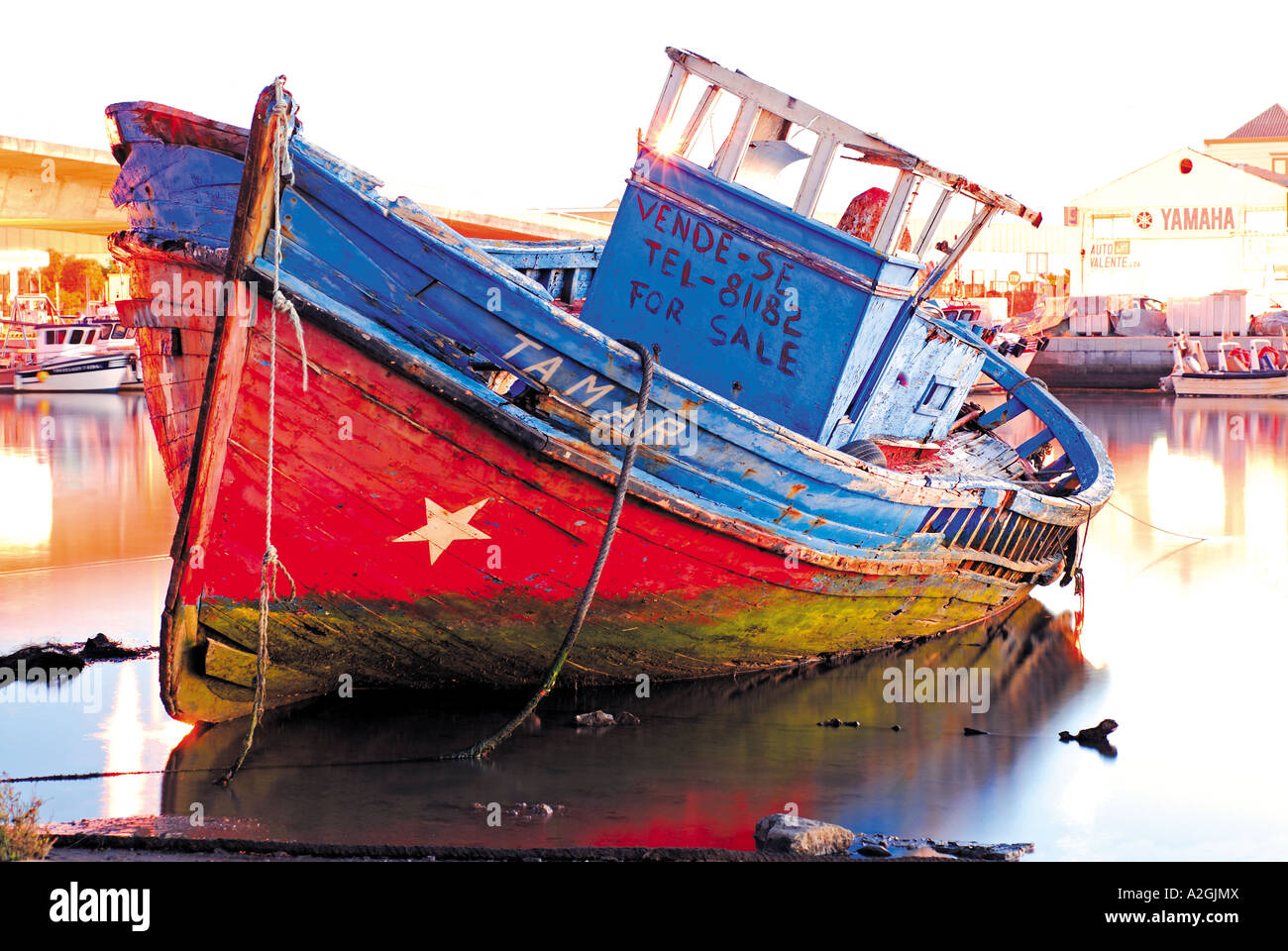 Old boat anchoring at low tide in the river Gilao, dawn in the harbour of Tavira, Algarve, Portugal Stock Photo