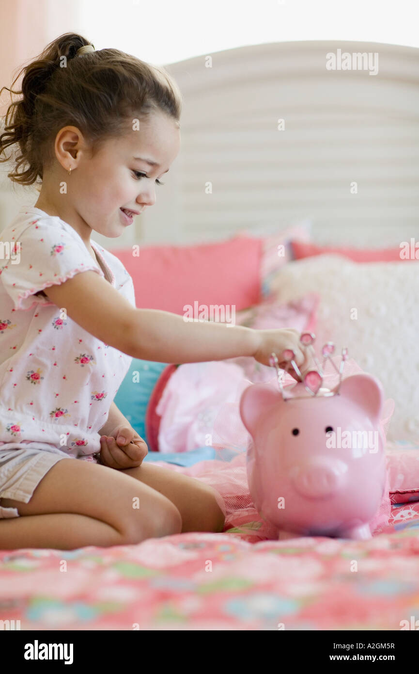 Young girl putting money in piggy bank Stock Photo - Alamy