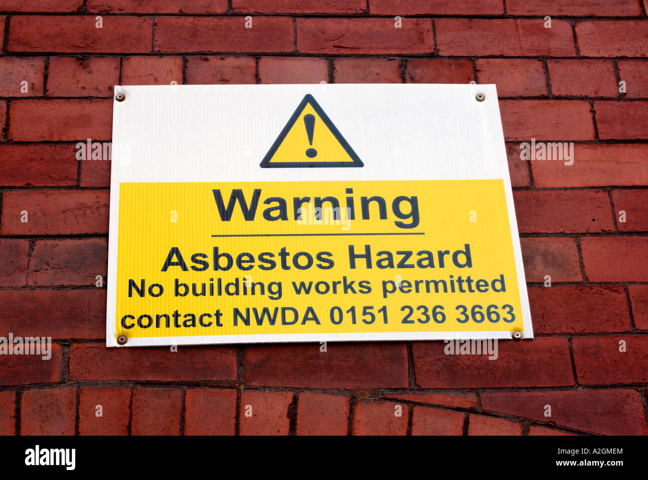 Sign warning of asbestos hazards in an old and listed mill building in the Ancoats area of East Manchester UK Stock Photo