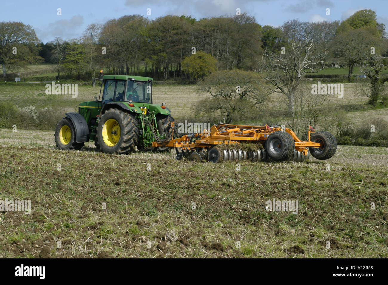 A John Deere tractor and disc harrow cultivating set aside land before