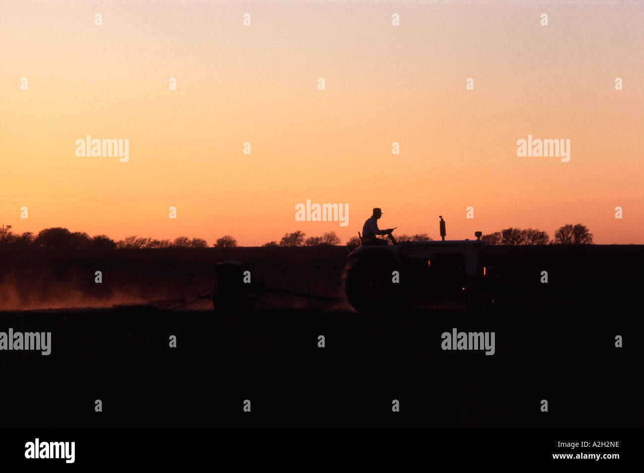 A farmer on his tractor works his field as the sun sets Stock Photo - Alamy