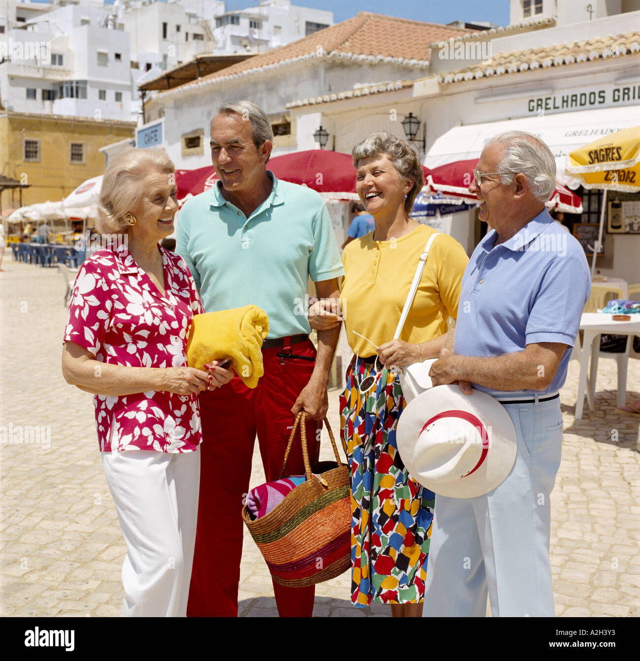 Senior Couples Of Retirement Age Chatting On Holiday In Street Senior Couples Of Retirement Age Chatting On Holiday In Street