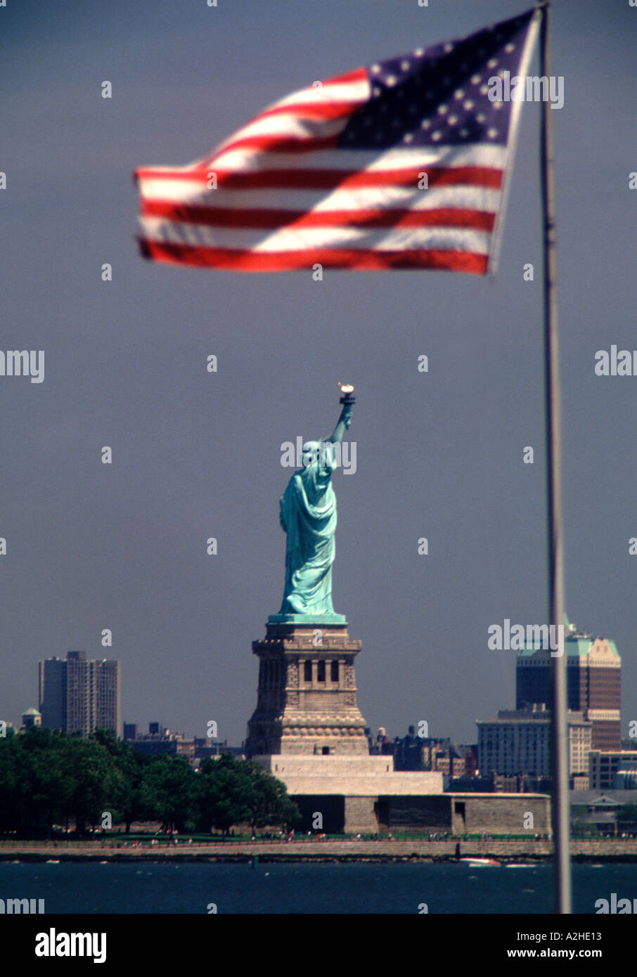 The Statue of Liberty stands in the distance beneath a U flag flying on