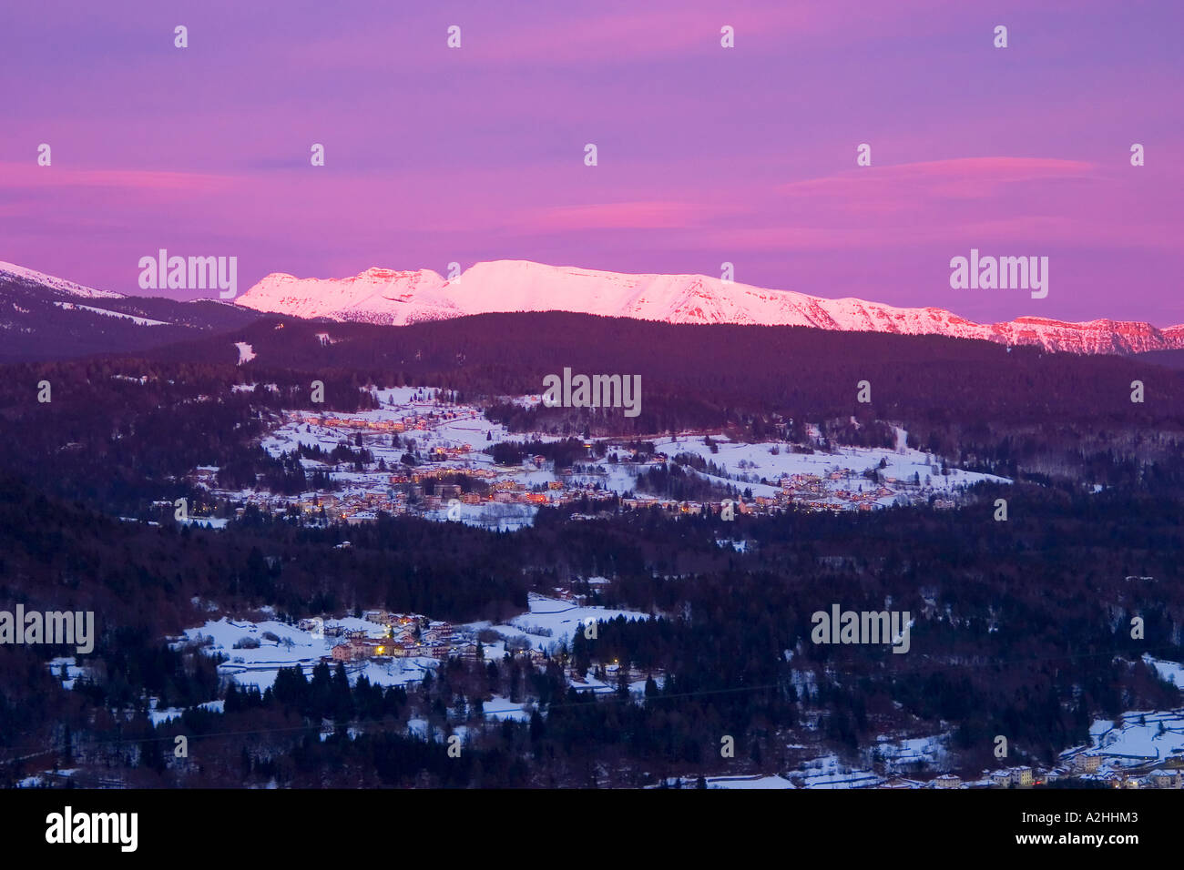 Panorama with mountains sunset clouds tree and smooth blue sky in winter altopiano di lavarone Stock Photo