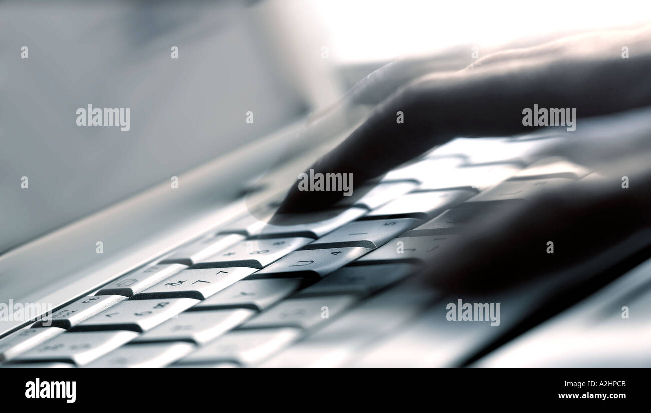 Landscape shot of laptop keyboard at low angle with hand adove showing movement Stock Photo