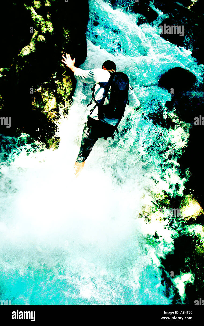 Male age 20-25 climbing a waterfall. The Image is in color and is portrait format. Stock Photo