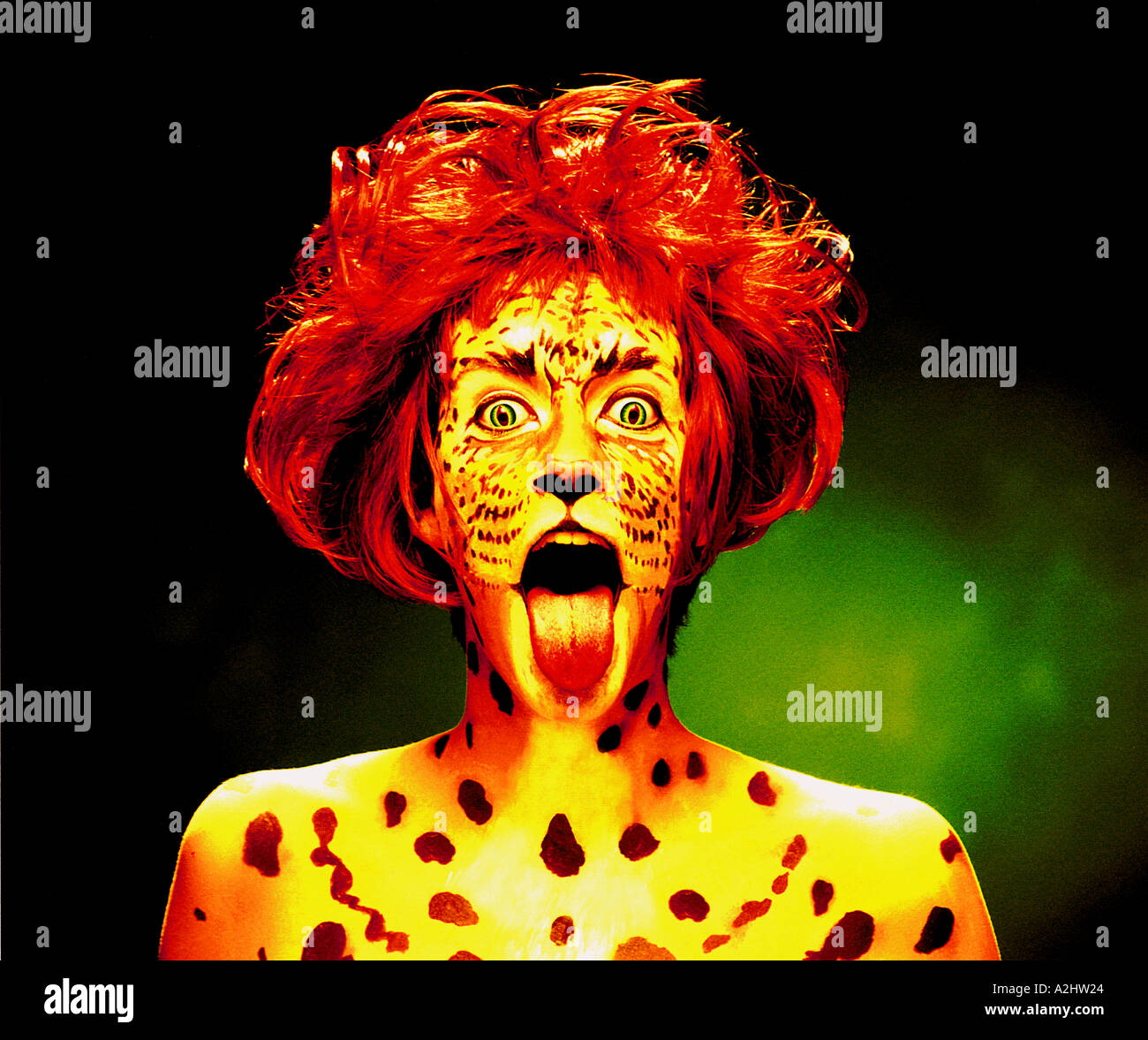 Woman age 20-25 with her face painted as a Tiger. She is wearing a red wig and has her tongue out. Stock Photo